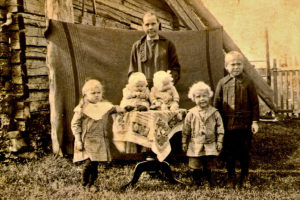 Vanha valokuva, jossa on ulkona nainen ja viisi lasta